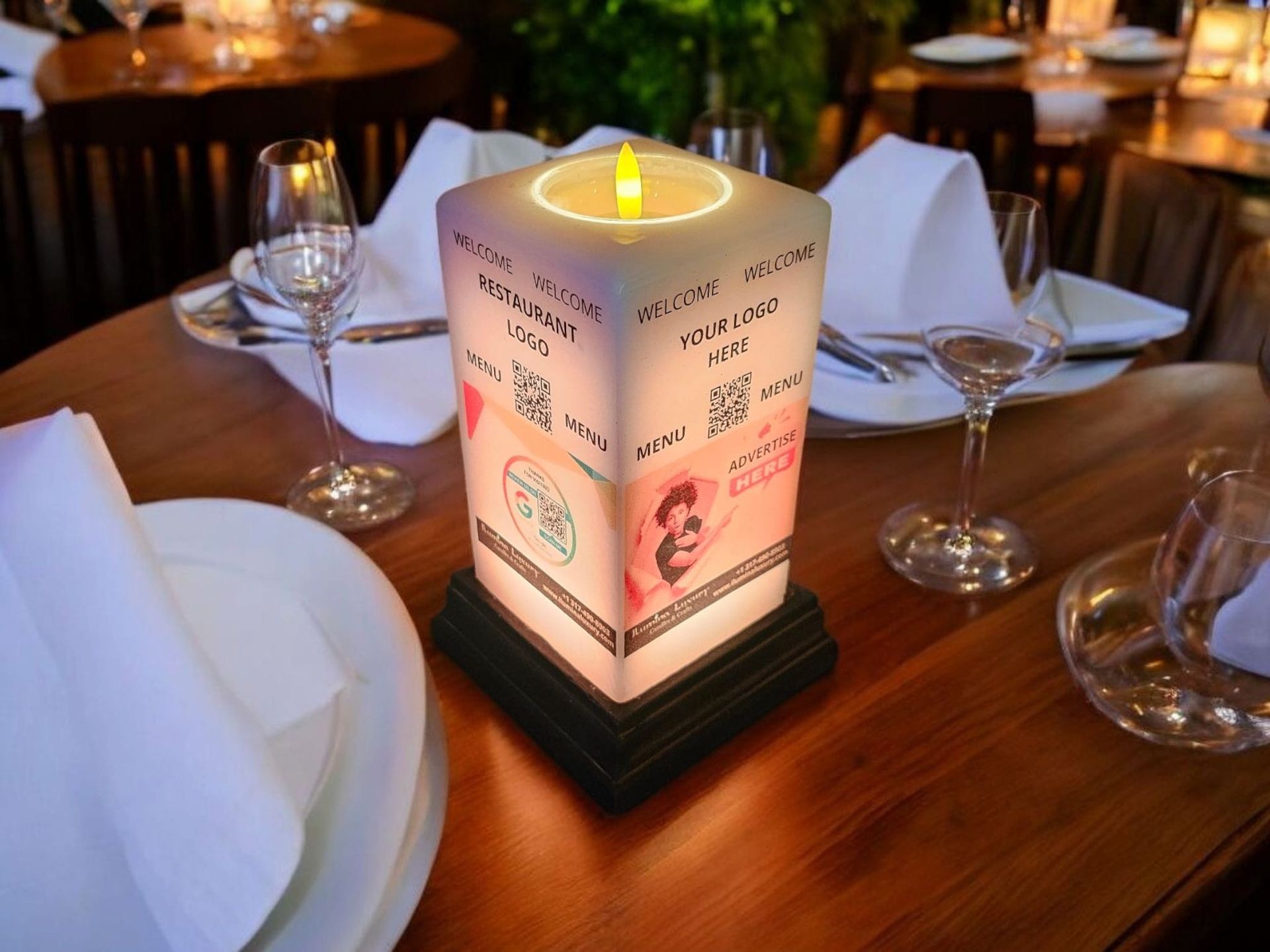 Table setting with candle lamp showing restaurant advertisement and QR code, surrounded by glasses and plates.